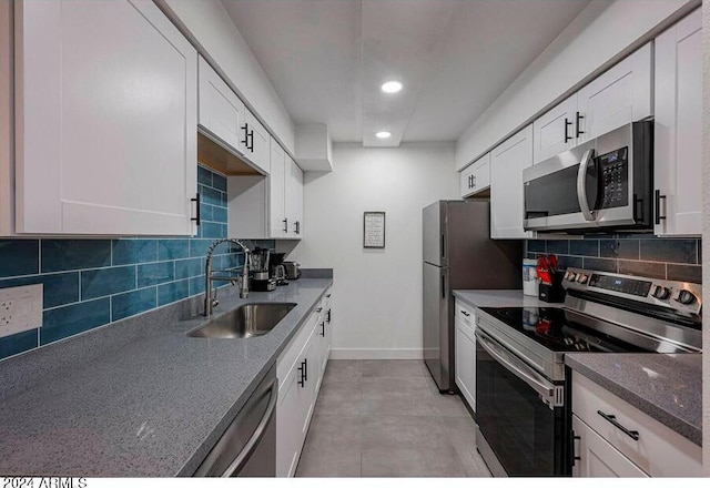 kitchen with white cabinetry, decorative backsplash, stainless steel appliances, and sink