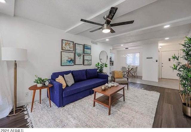 living room featuring dark wood-type flooring, ceiling fan, and beamed ceiling