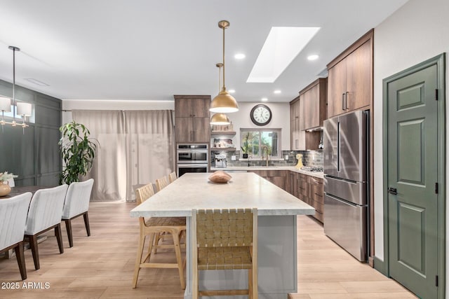 kitchen featuring pendant lighting, a skylight, a center island, and appliances with stainless steel finishes