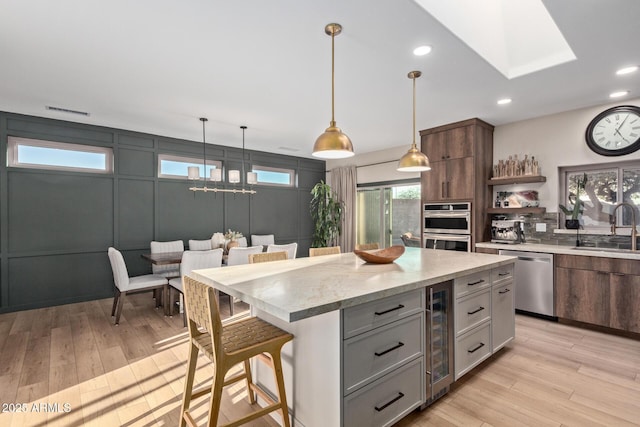 kitchen with a breakfast bar, sink, beverage cooler, a center island, and stainless steel appliances