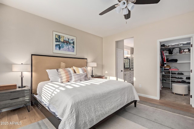 bedroom with a walk in closet, ensuite bath, light wood-type flooring, and a closet