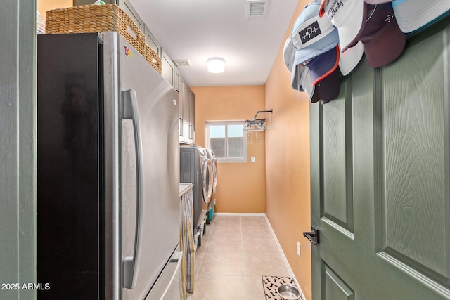 laundry area with cabinets, washing machine and dryer, and light tile patterned floors