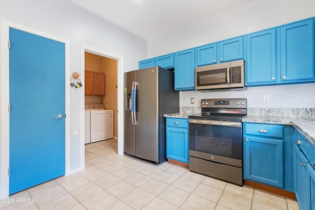 kitchen featuring blue cabinets, light tile patterned floors, light stone countertops, stainless steel appliances, and washer and clothes dryer