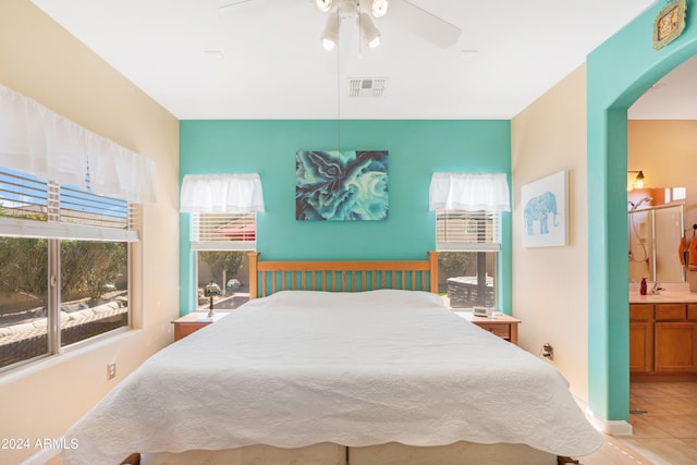 bedroom featuring light tile patterned flooring, ensuite bathroom, and ceiling fan