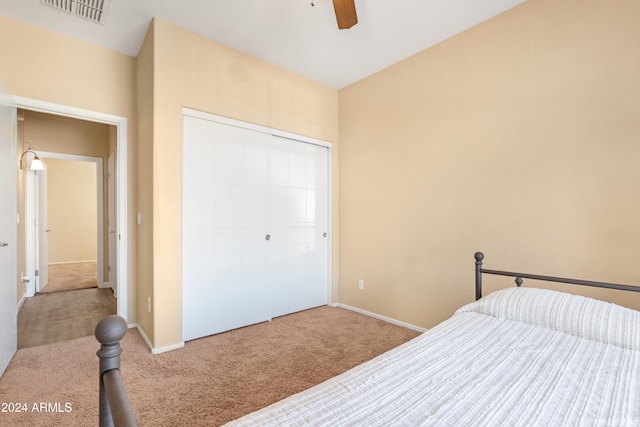 bedroom featuring light colored carpet, ceiling fan, and a closet