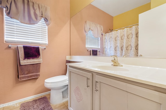 bathroom with tile patterned flooring, a healthy amount of sunlight, vanity, and toilet