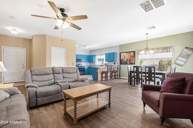 living room with ceiling fan with notable chandelier and hardwood / wood-style floors