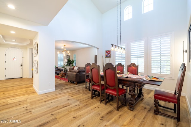 20639 W Grandview Dr, Buckeye, AZ 85396 - dining space with arched walkways, a chandelier, high vaulted ceiling, light wood-type flooring, and baseboards