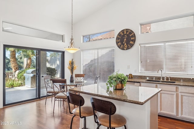 kitchen featuring a kitchen bar, sink, dark stone countertops, a kitchen island, and pendant lighting