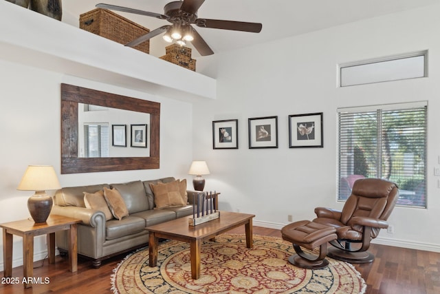 living room with dark wood-type flooring, ceiling fan, and a towering ceiling