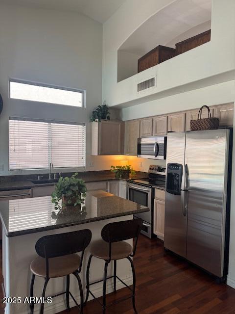 kitchen with a breakfast bar, sink, high vaulted ceiling, dark hardwood / wood-style flooring, and stainless steel appliances