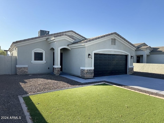 view of front of house featuring central air condition unit, a garage, and a front lawn