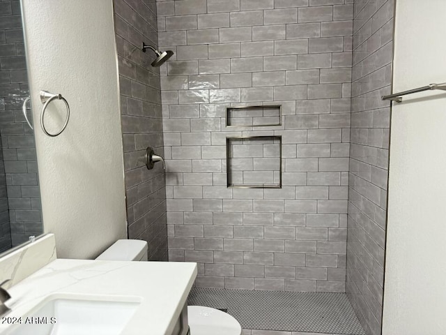 bathroom featuring tiled shower, vanity, and toilet