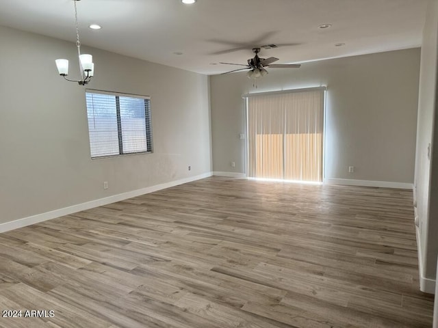 empty room featuring ceiling fan with notable chandelier and hardwood / wood-style floors