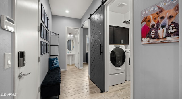 clothes washing area featuring cabinets, sink, washer / clothes dryer, and a barn door