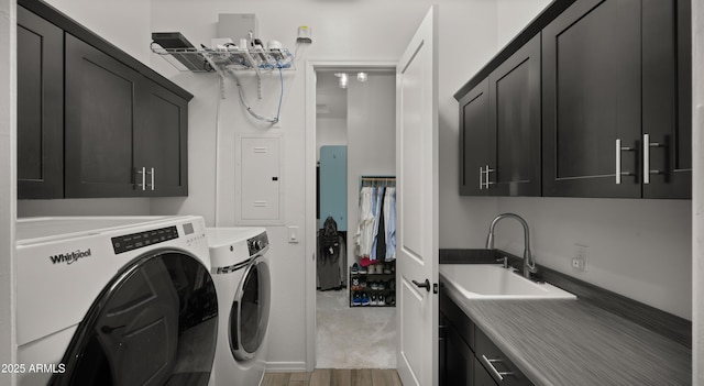 laundry area with sink, electric panel, cabinets, separate washer and dryer, and light wood-type flooring