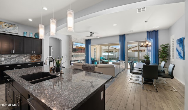 kitchen featuring dark stone countertops, pendant lighting, sink, and a center island with sink