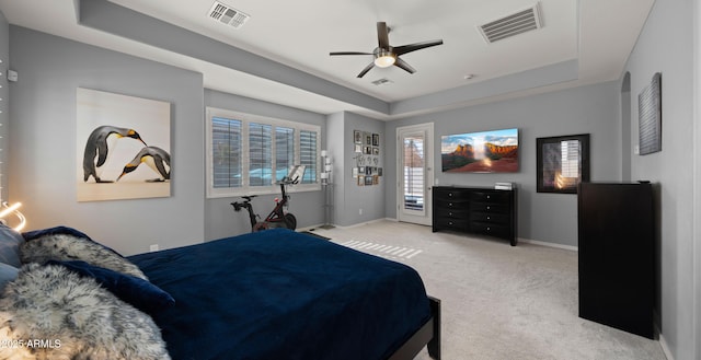 bedroom featuring a tray ceiling, light colored carpet, and ceiling fan