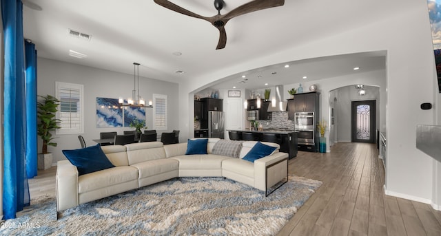 living room featuring hardwood / wood-style flooring and ceiling fan with notable chandelier