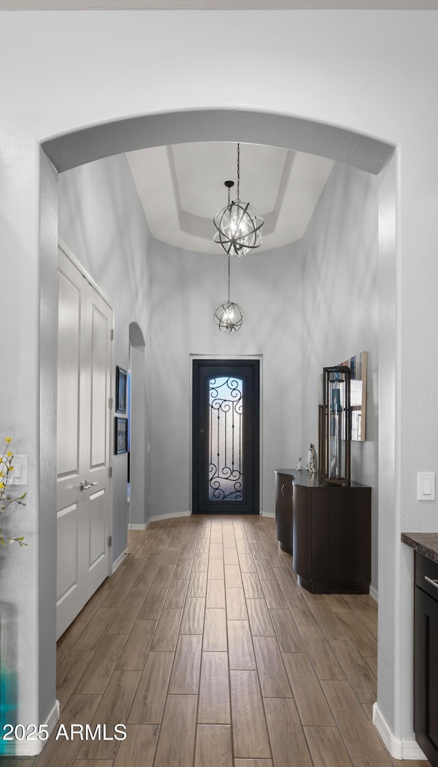 entrance foyer with an inviting chandelier, a towering ceiling, and a raised ceiling