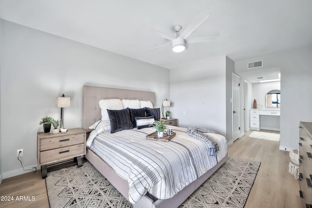 bedroom featuring ceiling fan, light hardwood / wood-style floors, and ensuite bath