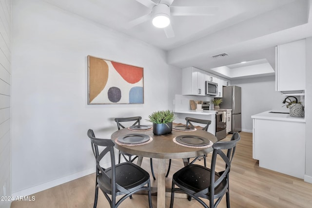 dining room with ceiling fan, light wood-type flooring, and sink