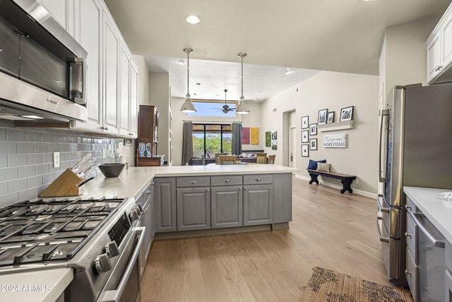 kitchen with gray cabinetry, white cabinets, hanging light fixtures, kitchen peninsula, and stainless steel appliances