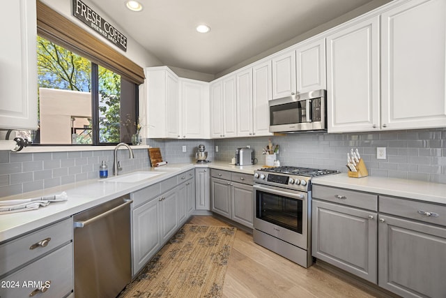 kitchen featuring sink, light hardwood / wood-style flooring, appliances with stainless steel finishes, gray cabinetry, and white cabinetry