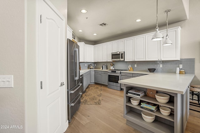 kitchen featuring appliances with stainless steel finishes, pendant lighting, white cabinets, and backsplash