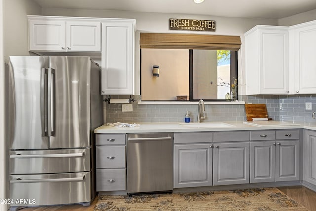 kitchen with sink, white cabinetry, gray cabinetry, stainless steel appliances, and decorative backsplash