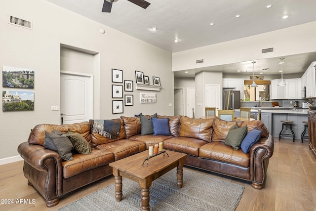 living room with ceiling fan, sink, and light hardwood / wood-style floors