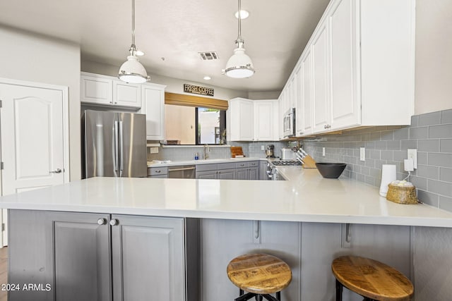 kitchen with decorative light fixtures, a breakfast bar area, white cabinets, and appliances with stainless steel finishes