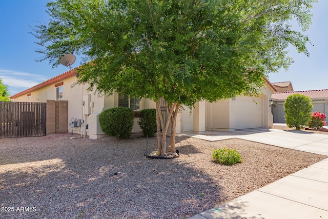 view of front of property with stucco siding, concrete driveway, a garage, a tile roof, and a gate