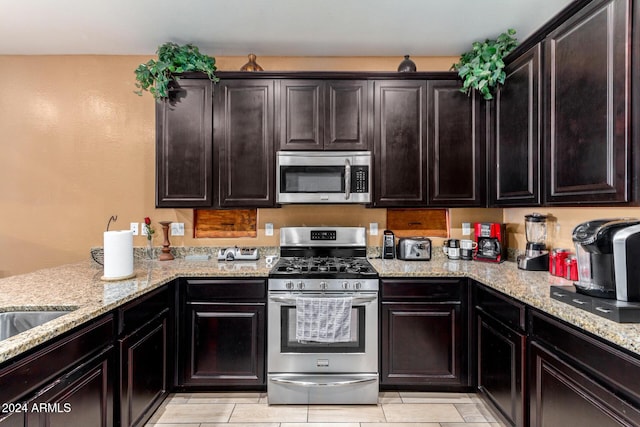 kitchen featuring light stone countertops, dark brown cabinetry, and stainless steel appliances