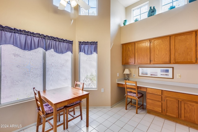 kitchen featuring a towering ceiling, built in desk, light tile patterned flooring, and ceiling fan