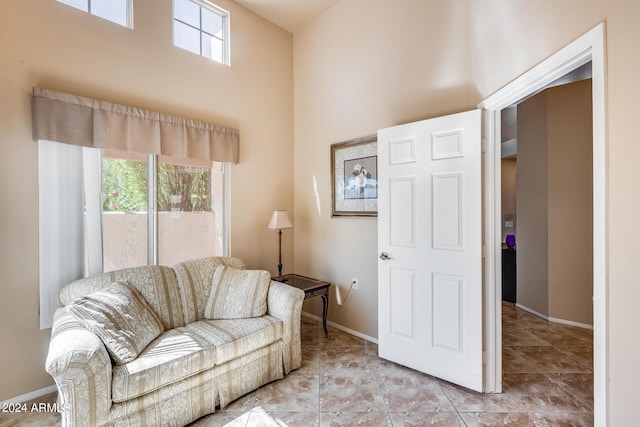 living room featuring a wealth of natural light, baseboards, and a towering ceiling