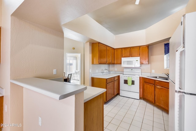 kitchen featuring light tile patterned floors, white appliances, kitchen peninsula, and sink