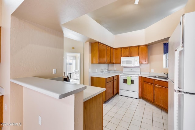 kitchen with white appliances, light tile patterned floors, brown cabinetry, a peninsula, and light countertops