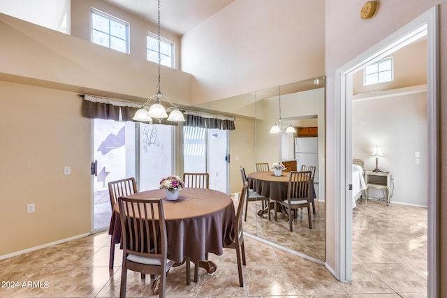 dining area with light tile patterned floors, baseboards, a chandelier, and a towering ceiling