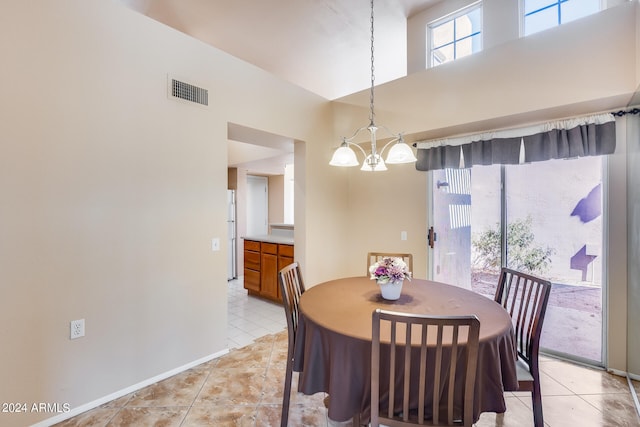 tiled dining space with a notable chandelier and a towering ceiling