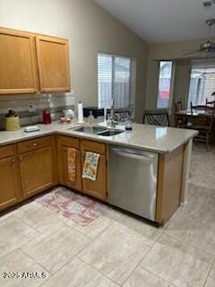 kitchen featuring kitchen peninsula, stainless steel dishwasher, vaulted ceiling, a healthy amount of sunlight, and sink