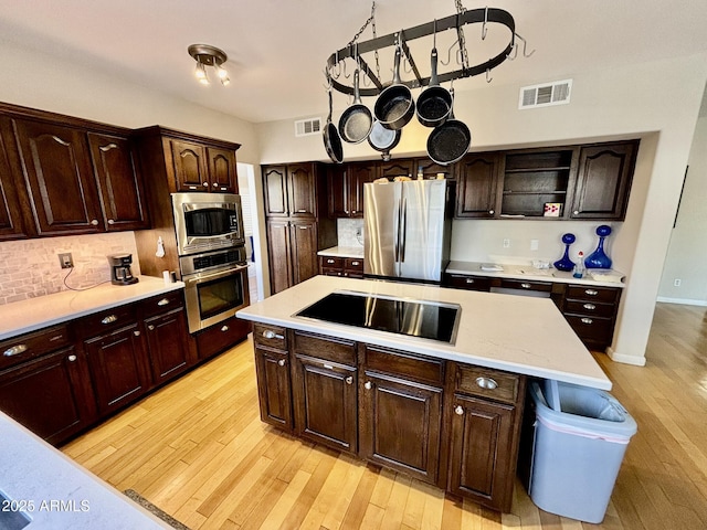 kitchen featuring a kitchen island, dark brown cabinetry, and appliances with stainless steel finishes