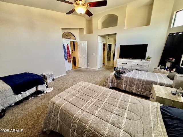 carpeted bedroom with ceiling fan and a towering ceiling