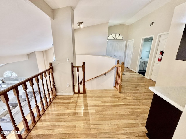 hallway with light hardwood / wood-style flooring and vaulted ceiling