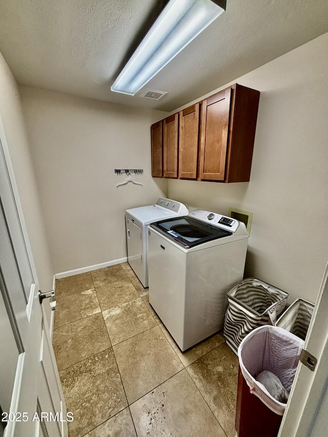 laundry room with separate washer and dryer, cabinets, and a textured ceiling