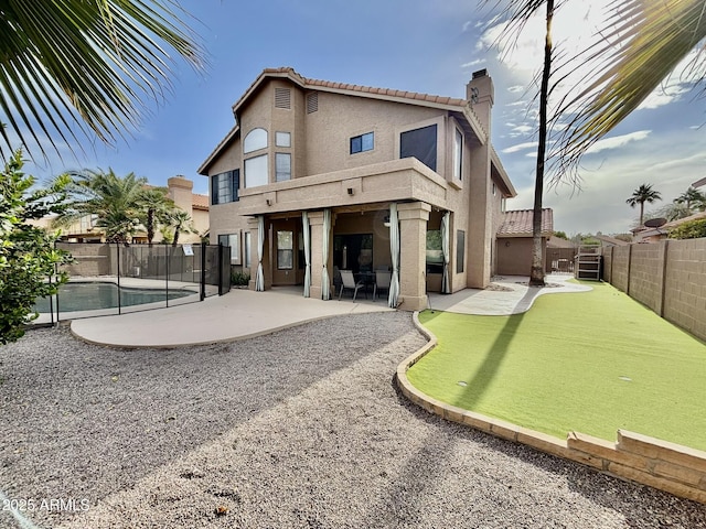 back of property featuring a fenced in pool and a patio area