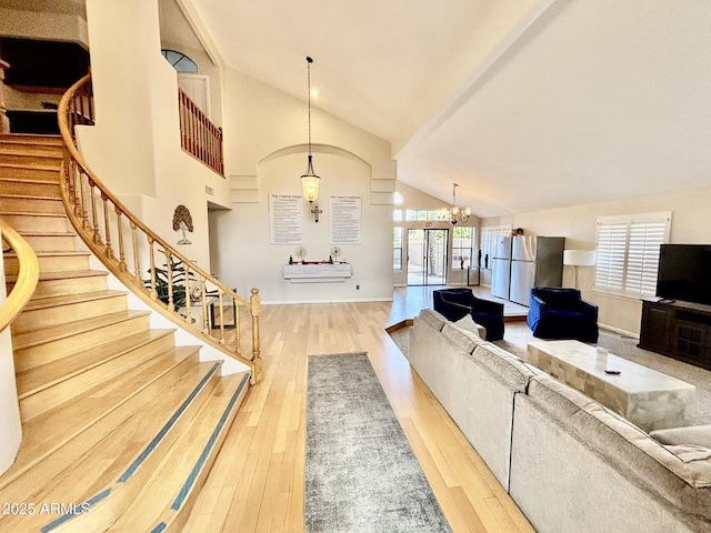 living room with hardwood / wood-style floors, an inviting chandelier, high vaulted ceiling, and french doors