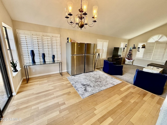 dining room with light wood-type flooring, lofted ceiling, and an inviting chandelier