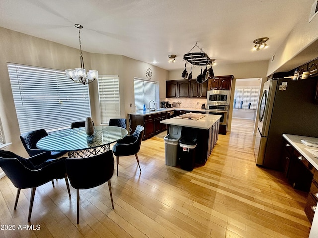 dining area featuring light hardwood / wood-style flooring, an inviting chandelier, a healthy amount of sunlight, and sink