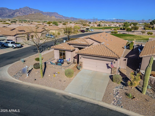 view of front facade featuring a mountain view, a garage, a tile roof, driveway, and stucco siding